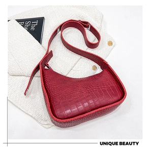 Detail of burgundy crocodile-textured leather on a vintage hobo shoulder bag