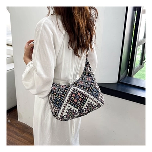Sac hobo en tricot ethnique aux motifs géométriques porté par un mannequin en robe blanche