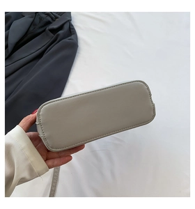 Detailed base view of a shell-shaped crossbody bag featuring precise stitching and studs