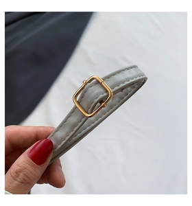 Detail of adjustable grey PU leather shoulder strap with gold metal buckle and stitching