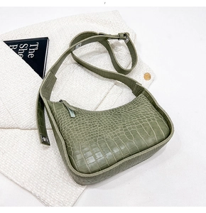 Detail of sage green crocodile pattern leather hobo bag on white tweed fabric
