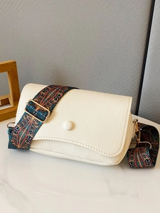 Close-up of white pebble leather bag with colorful Bohemian wide shoulder strap