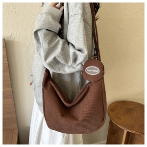 Detail of a brown corduroy crescent bag showing a small round coin purse and soft fabric texture