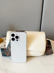 White pebbled leather shoulder bag with ethnic strap and smartphone for scale