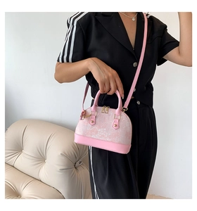Detailed view of pink shell-shaped crossbody bag with floral pattern and golden metal rivets