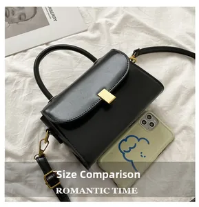 Size comparison of a black leather crossbody bag with gold lock on a white fabric surface