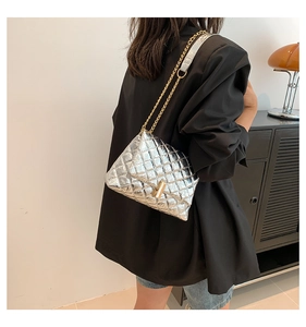 Détail du sac bandoulière argenté matelassé avec chaîne dorée et fermoir cylindrique