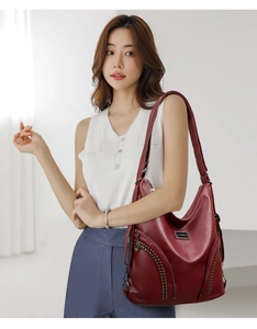 Detail of dark burgundy PU leather hobo bag with metal rivets and zipper decorations
