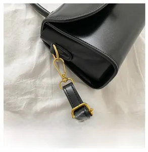 Detail of reinforced gold hardware and adjustable leather strap on a black crossbody bag