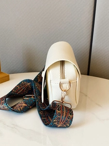 Close-up of white lychee leather texture and colorful geometric strap with gold zipper