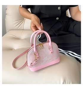 Detail of pink shell bag featuring embossed floral patterns and gold metal zippers