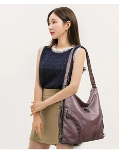 Detail of grey-purple PU leather tote bag with rivets and zipper shown on model