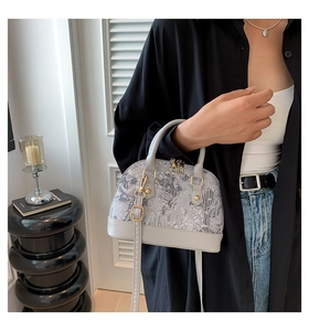 Detailed shot of grey jacquard shell bag with gold zippers and detachable strap