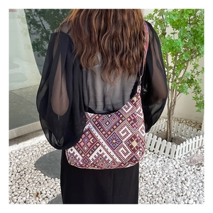 Gros plan sur un sac bandoulière en jacquard ethnique avec motifs géométriques bordeaux