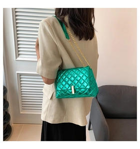 Détail d'un sac bandoulière matelassé vert vif avec chaîne dorée porté par un mannequin