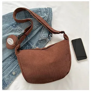 Detail of brown corduroy crescent bag with a round coin purse and smartphone for size