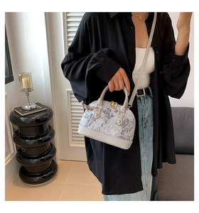 Detailed view of the gray shell-shaped bag with intricate patterns and golden hardware