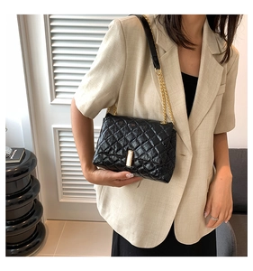 Détail du sac à bandoulière noir matelassé avec chaîne dorée et cuir synthétique poli