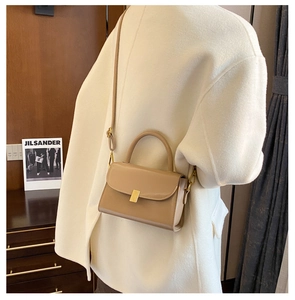 Detail of a minimalist khaki square bag with a golden lock and slim adjustable shoulder strap