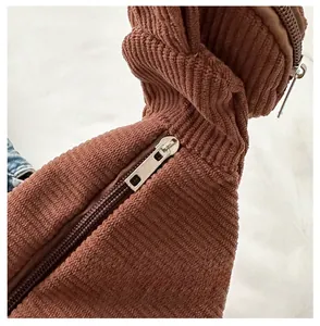 Detailed macro view of the brown corduroy fabric and smooth silver metal zipper on bag