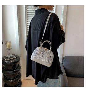Close-up of printed shell-shaped handbag with adjustable strap on a female model