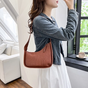 Brown crocodile pattern hobo shoulder bag shown on model in a bright interior setting
