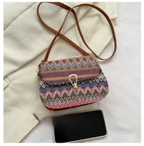 Close-up of ethnic crossbody bag with multicolored weave and size comparison to phone