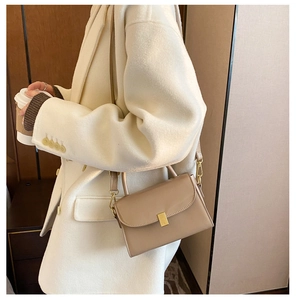 Model wearing a khaki rectangular leather crossbody bag with a gold clasp and metal handle