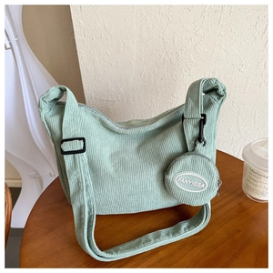 Close-up of mint green corduroy crossbody bag texture and matching mini round coin purse