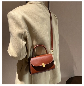 Brown leather crossbody bag detail on model wearing a beige textured blazer