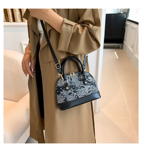 Detailed view of the embroidered shell bag with studs worn by a model in a trench coat