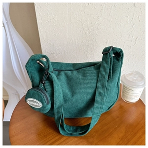Detail of dark green corduroy shoulder bag with matching round coin purse on a wooden table