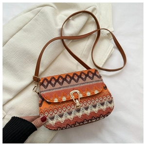 Detailed close-up of ethnic woven pattern and golden drop-shaped clasp on a crossbody bag