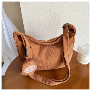Close-up of orange corduroy shoulder bag showing zipper and round pendant pouch