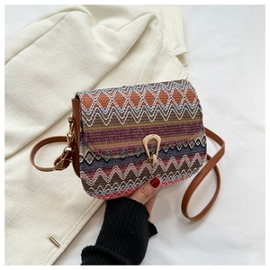 Detail of bohemian woven crossbody bag featuring colorful patterns and horseshoe buckle