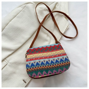 Macro shot of ethnic boho woven crossbody bag with colorful stripes and leather strap