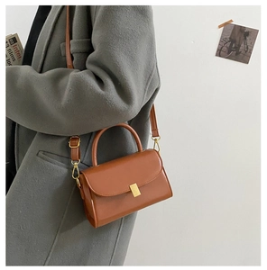 Detail of caramel leather small square bag with golden hardware and slender strap