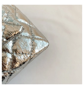 Gros plan d'un sac matelassé argenté avec texture cuir froissé et surpiqûres précises