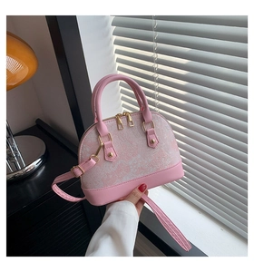 Close-up of pink shell-shaped handbag with white embroidery and golden metal zippers