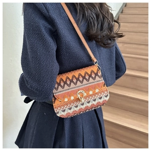 Rear view of model wearing ethnic woven crossbody bag with geometric patterns and metal clasp