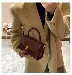 Close-up of retro reddish-brown leather crossbody bag with golden metal clasp detail