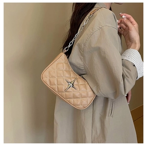 Detail of light khaki quilted crossbody bag with silver star and chain strap