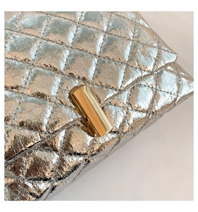 Détail de la texture argentée matelassée et fermoir métallique doré sur le sac chic