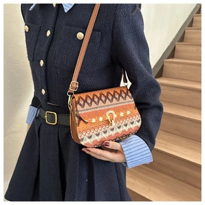 Close-up of bohemian woven crossbody bag featuring a golden horseshoe lock and leather strap
