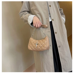 Detail of light brown quilted handbag with silver star ornament and chain strap