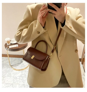 Detail of dark brown leather mini square bag with golden lock and thin shoulder strap