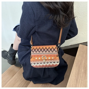 Close-up of a retro ethnic woven crossbody bag with geometric patterns and gold buckle