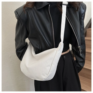 Detail of white corduroy hobo bag showing ribbed texture and adjustable strap on model