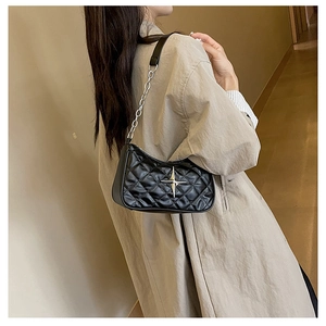 Detail of black quilted crossbody bag with silver star metal accent and chain strap