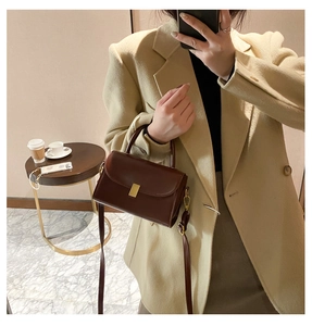 Detailed view of dark brown leather crossbody bag with elegant gold metal square buckle